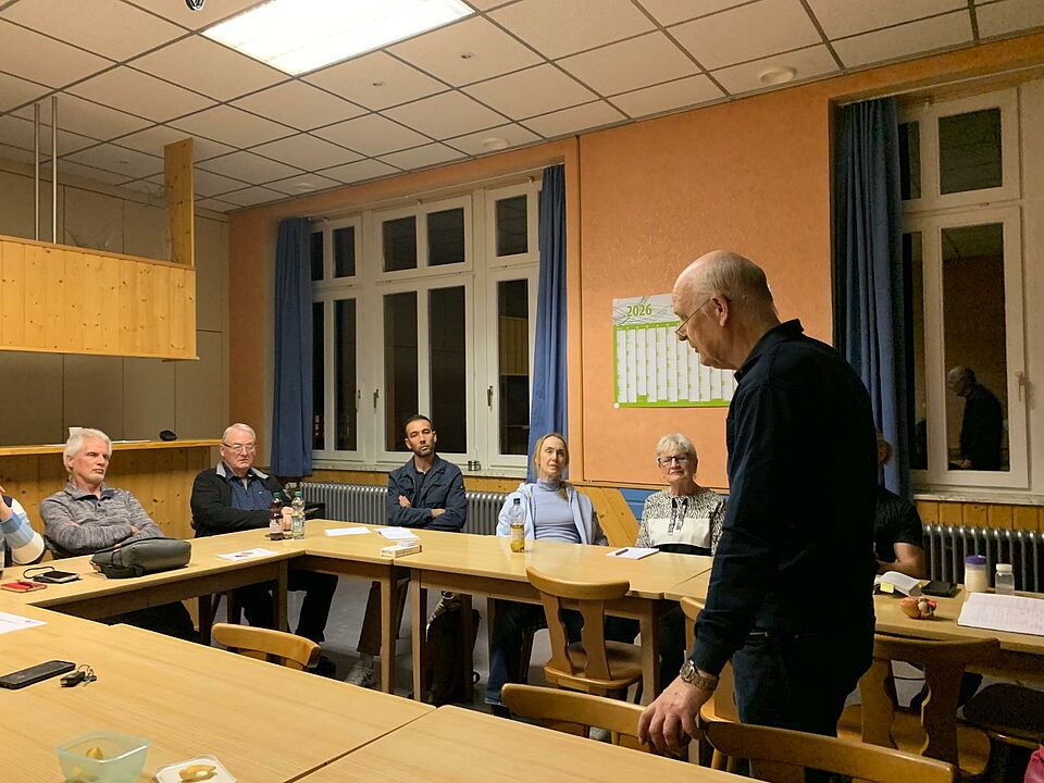 Ein Mann hält vor mehreren Personen einen Vortrag